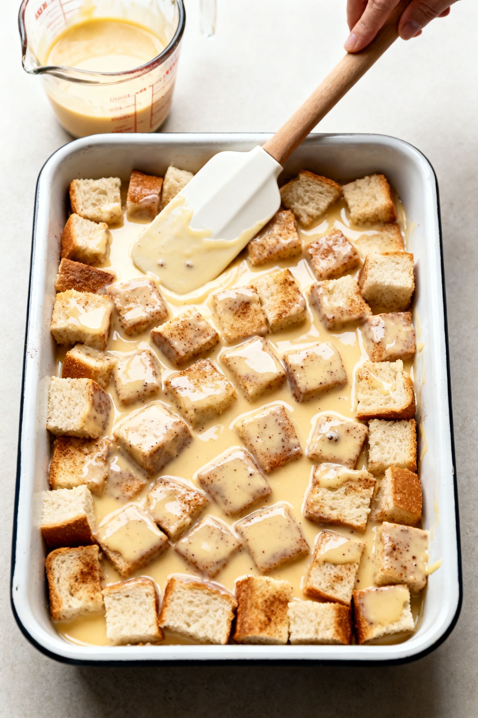 Cooking process: Overhead, action-focused shot of the soaked bread cubes being gently pressed and le