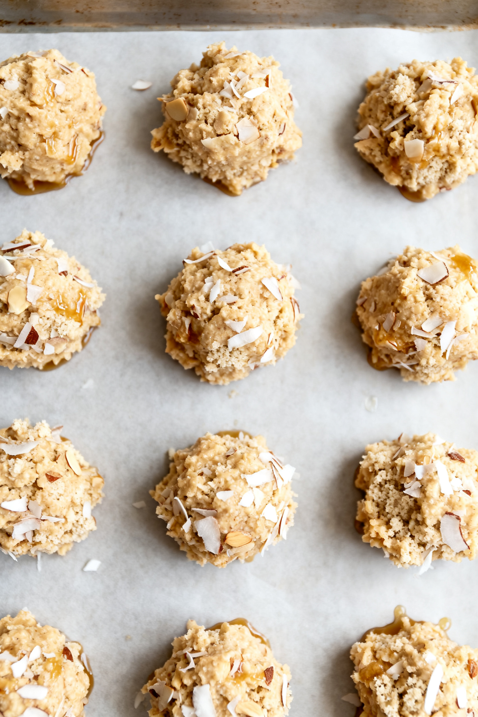 Cooking process: Overhead shot of compact mounds of macaroon mixture on a parchment-lined baking she