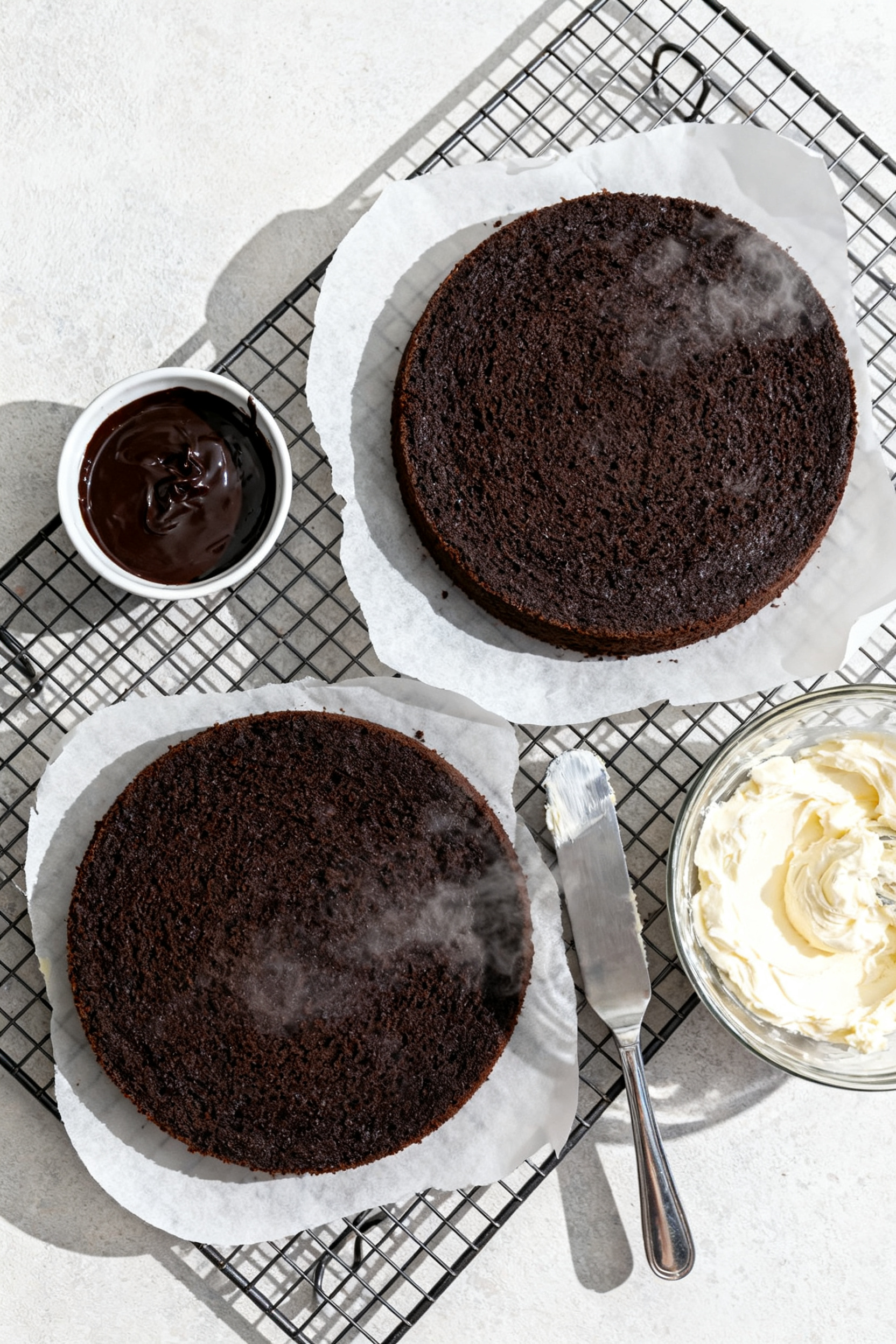 Cooking process: Overhead shot of two freshly baked 8-inch dark chocolate cake layers cooling on a w