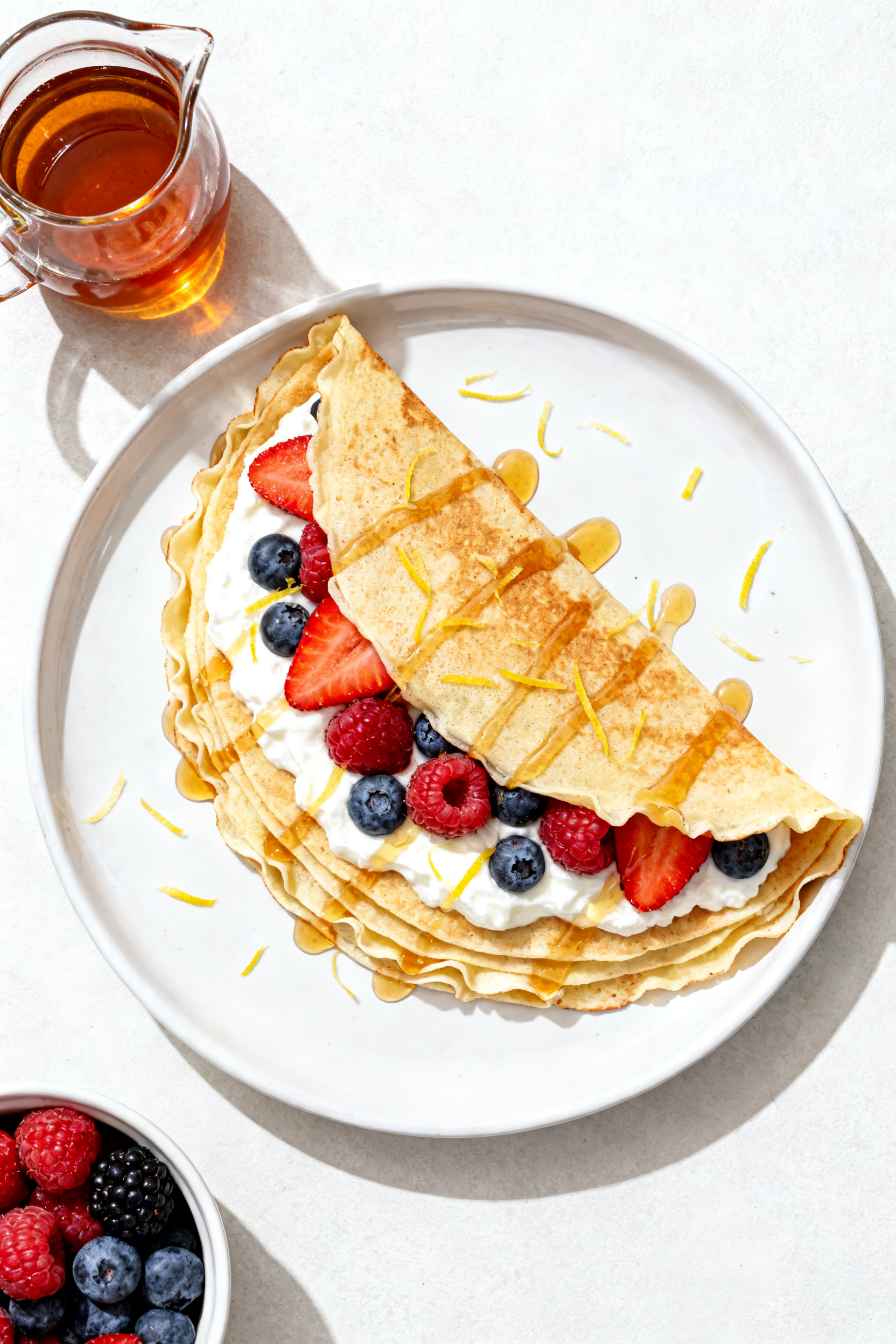 Overhead sweet stack: Top-down shot of a neat stack of protein crepes on a white ceramic plate, edge