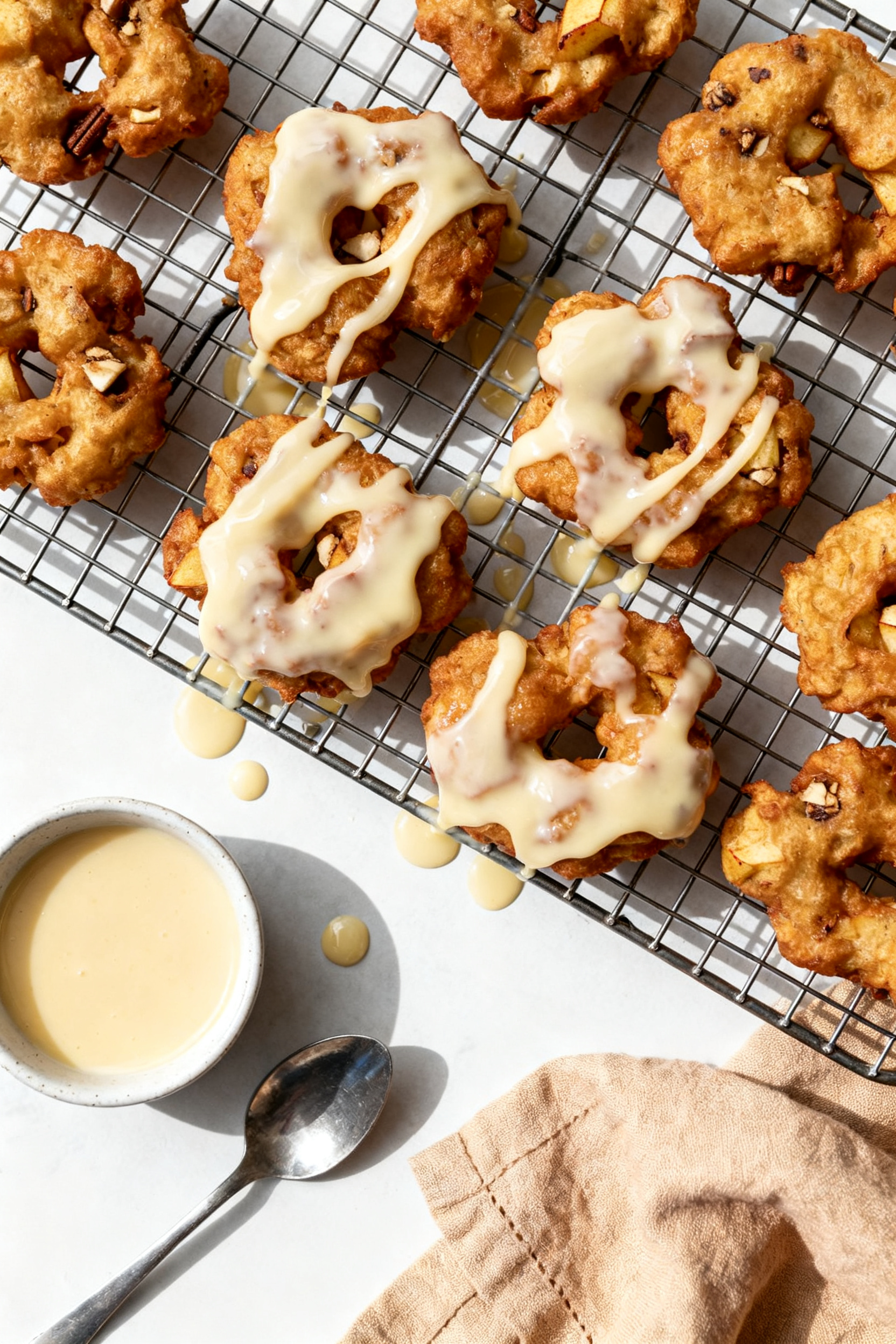 Tasty top view: Overhead shot of a wire rack holding freshly cooked apple fritters being glazed whil